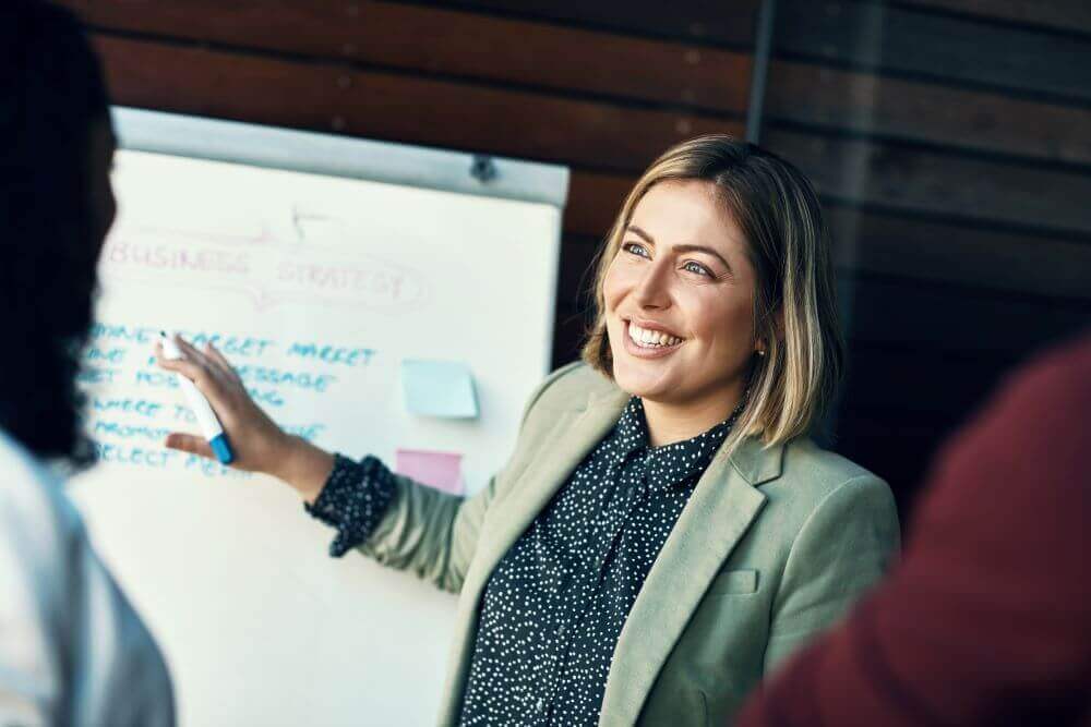 Woman at whiteboard explaining datamining concepts to the team